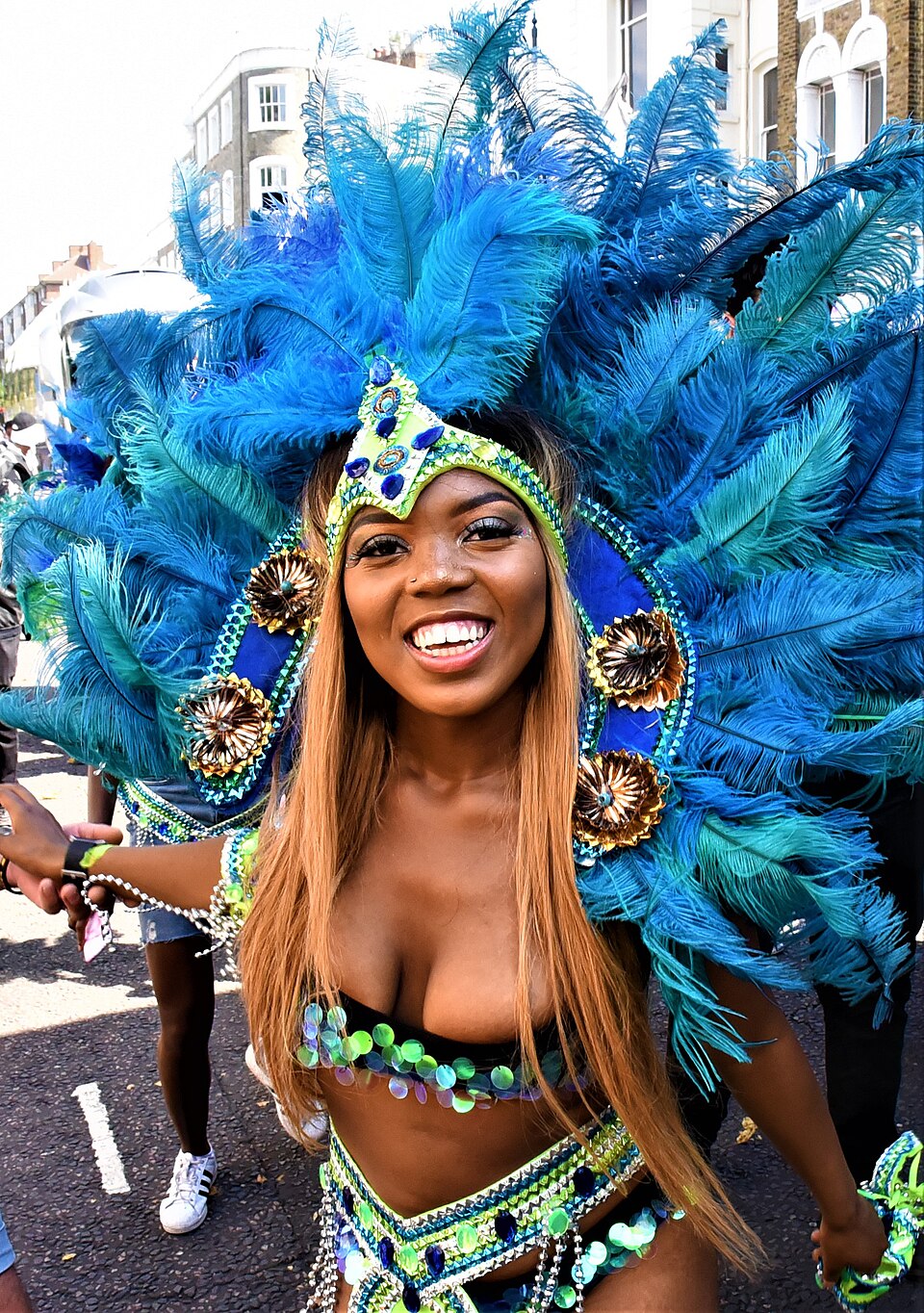 Masqueraders in feathered costumes moving along the Notting Hill Carnival parade route in west London.